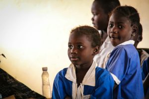 A group of children in school uniforms engaged in a classroom setting, focused and attentive.